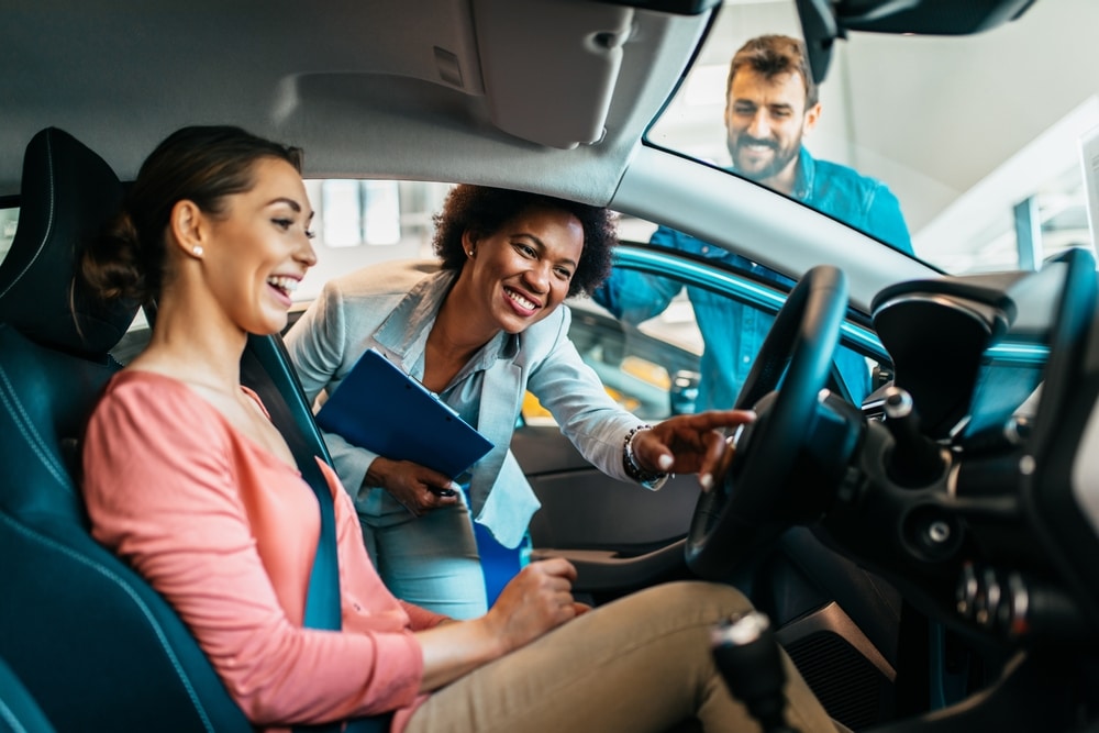Young,Couple,Talking,With,Saleswoman,At,Car,Showroom,About,New qualities of a car salesperson